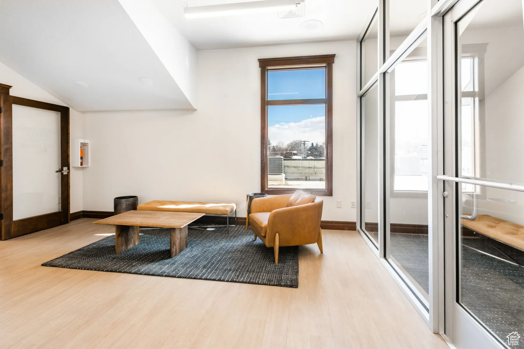 Living area featuring light wood-type flooring, baseboards, and vaulted ceiling