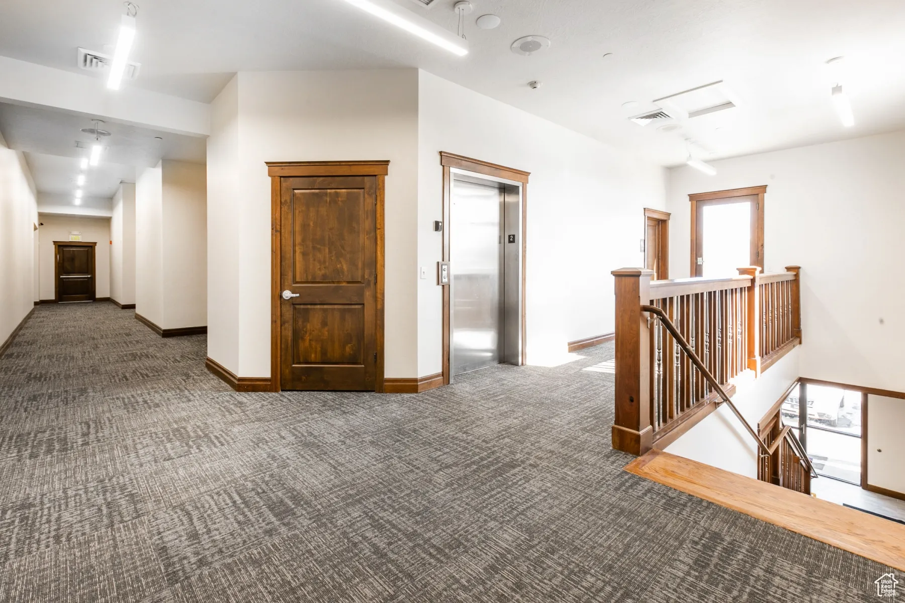 Hall featuring visible vents, carpet floors, an upstairs landing, baseboards, and elevator