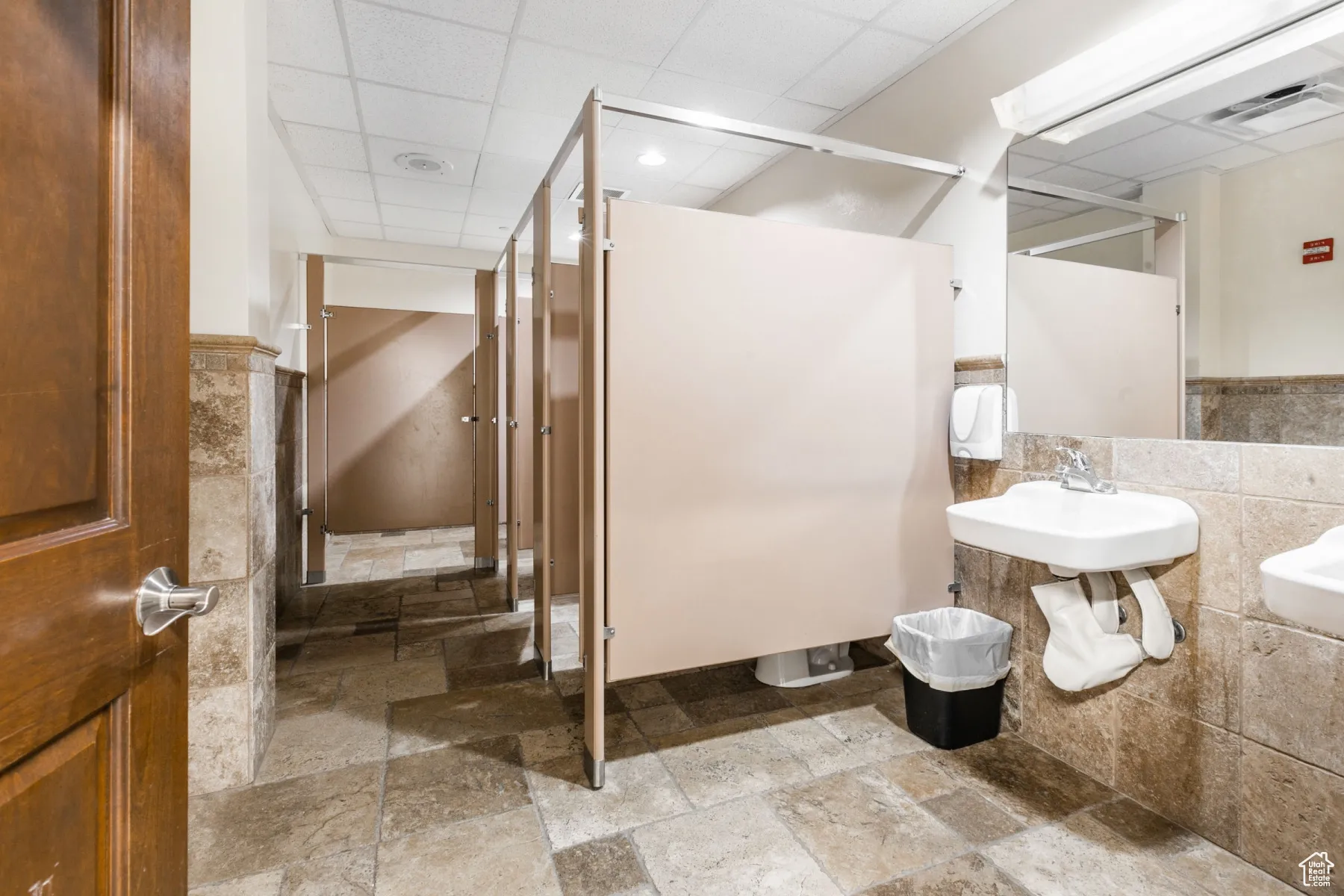 Bathroom with stone tile flooring, tile walls, and visible vents