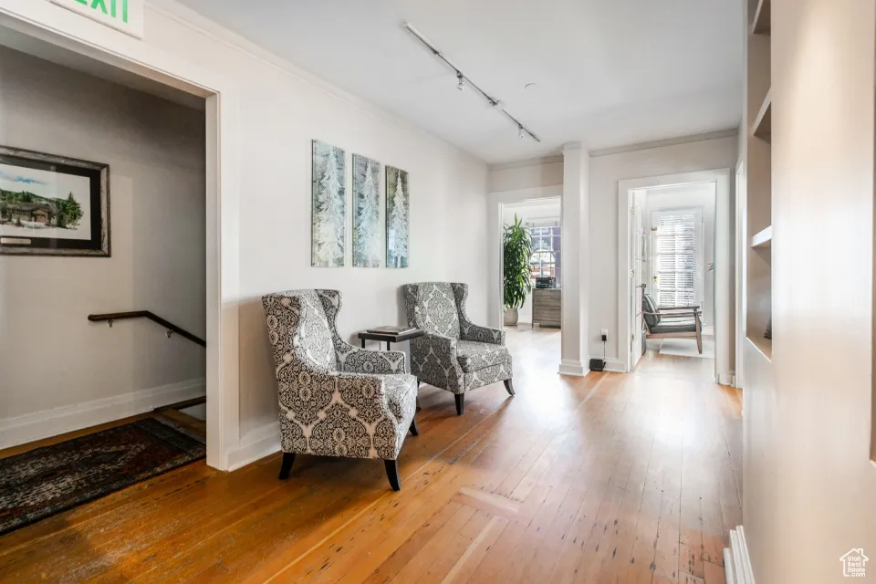 Sitting room with rail lighting, baseboards, hardwood / wood-style floors, and ornamental molding
