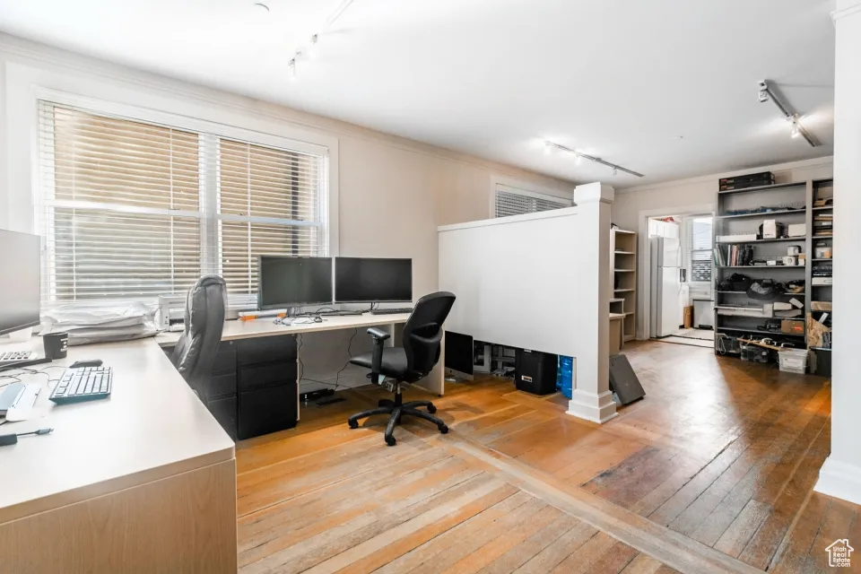 Office space with track lighting, light wood-style flooring, and a wealth of natural light