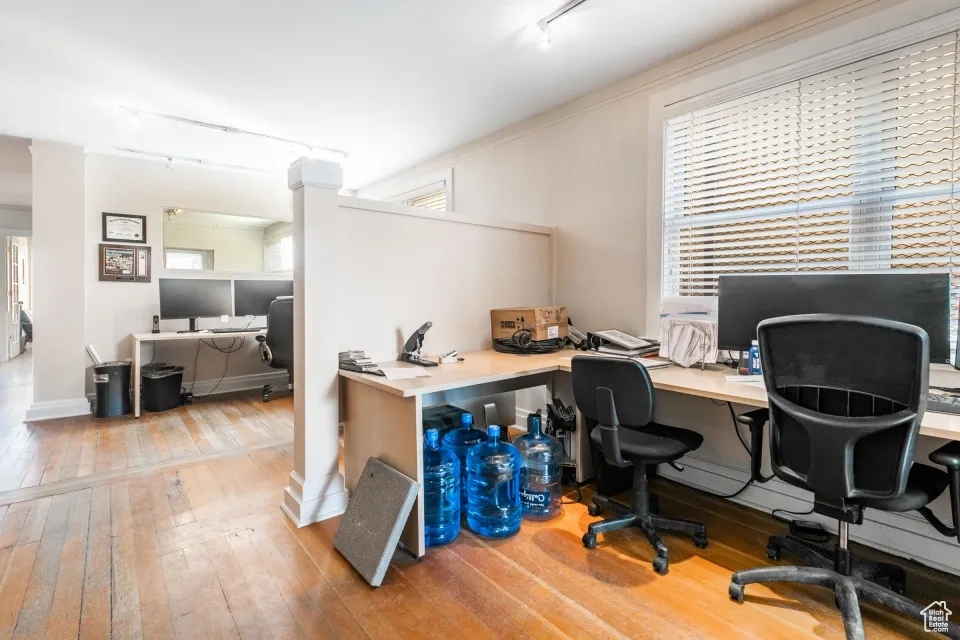 Office with wood-type flooring and track lighting