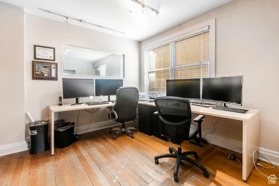 Office space featuring hardwood / wood-style floors, baseboards, and rail lighting