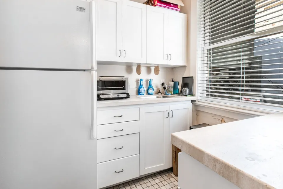 Kitchen featuring white cabinetry, light countertops, freestanding refrigerator, and a toaster