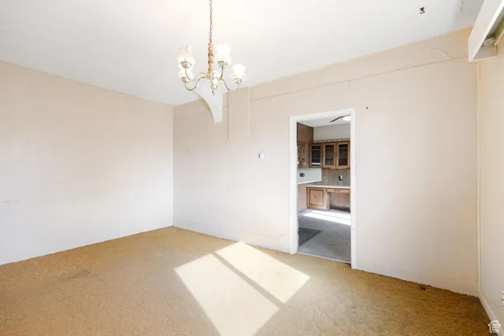 Spare room with an inviting chandelier and light carpet