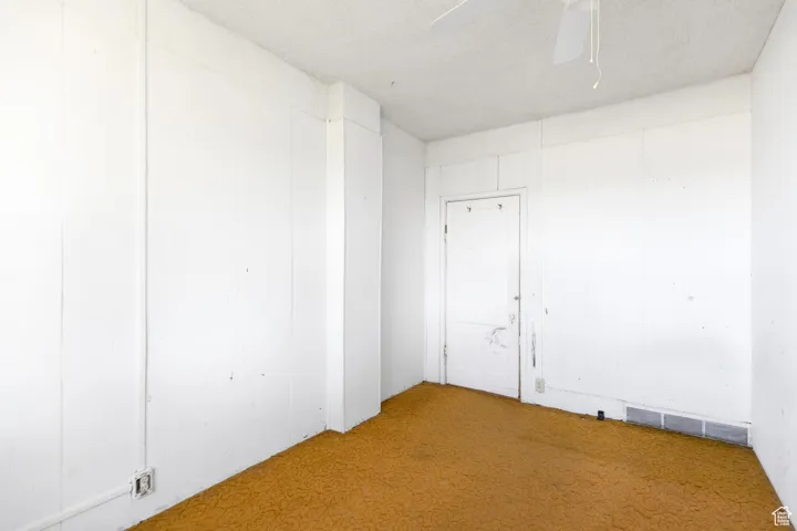 Empty room with a ceiling fan, carpet, and visible vents