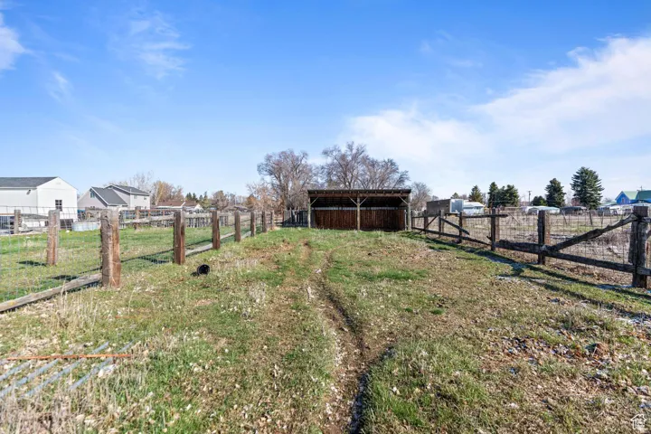 View of yard with an outbuilding, fence, a pole building, and a rural view