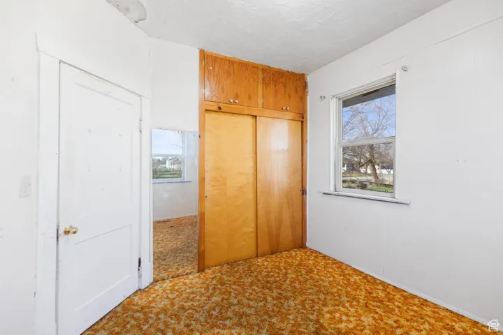 Unfurnished bedroom featuring a closet, a textured ceiling, and carpet