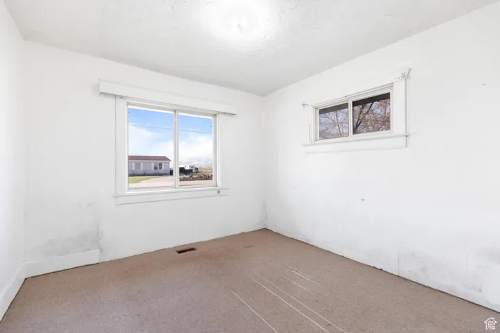 Carpeted spare room featuring visible vents and a textured ceiling