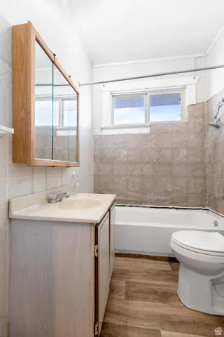Bathroom with toilet, plenty of natural light, vanity, and wood finished floors