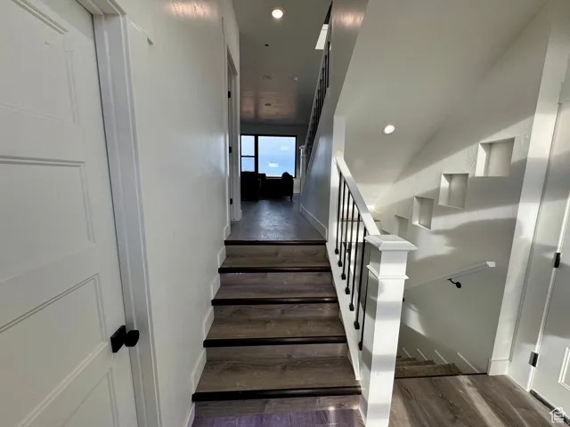 Staircase featuring wood finished floors, baseboards, and recessed lighting