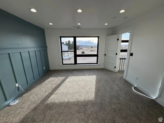 Unfurnished room with a wealth of natural light, recessed lighting, and dark carpet