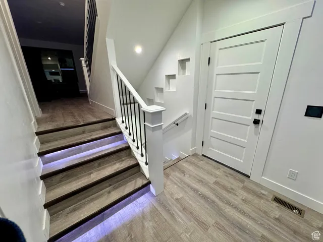 Staircase featuring wood finished floors, baseboards, and visible vents