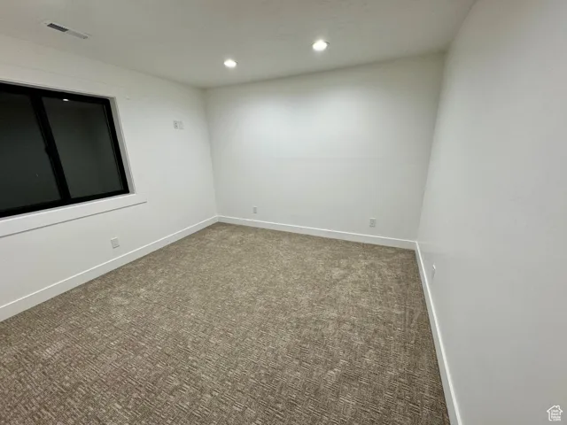Carpeted empty room featuring baseboards, visible vents, and recessed lighting
