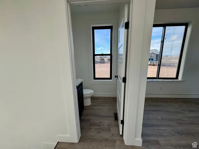 Bathroom featuring toilet, wood finished floors, vanity, and baseboards