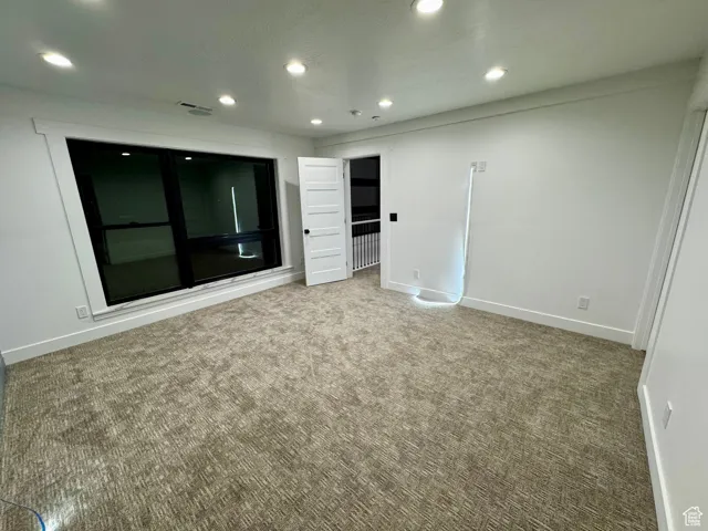 Carpeted spare room featuring baseboards, visible vents, and recessed lighting