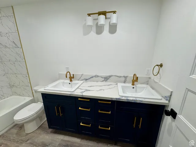 Full bathroom featuring toilet, double vanity, and a sink
