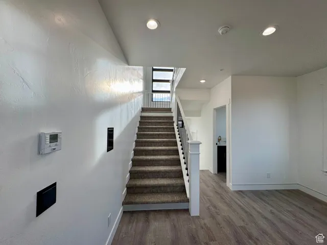 Stairway with recessed lighting, baseboards, and wood finished floors