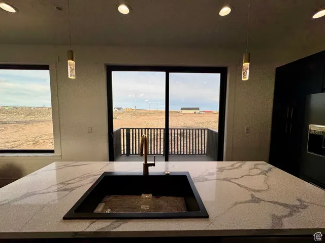 Kitchen featuring recessed lighting, pendant lighting, a sink, and light stone counters