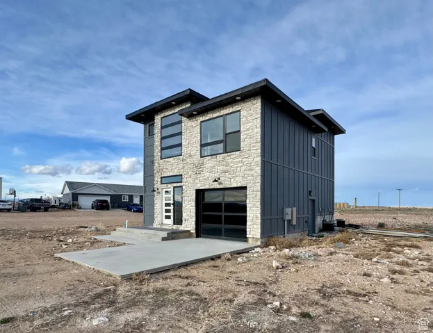 View of home's exterior with board and batten siding, an attached garage, stone siding, and concrete driveway