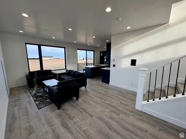 Living room with recessed lighting, stairway, baseboards, and wood finished floors