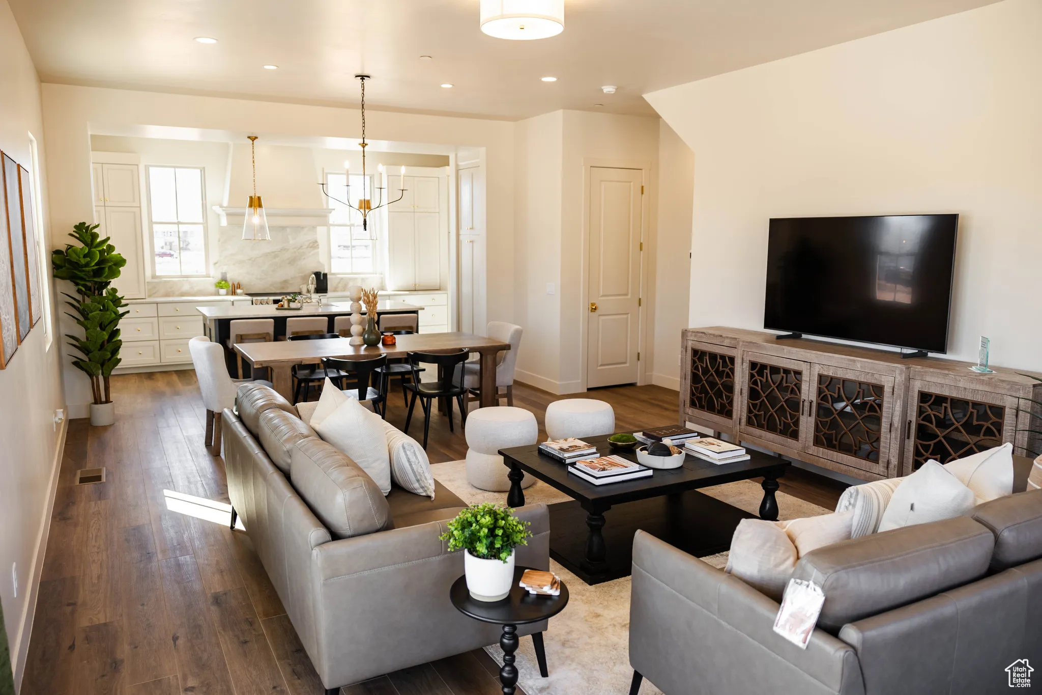 Living room with dark wood-type flooring, baseboards, recessed lighting, and a notable chandelier
