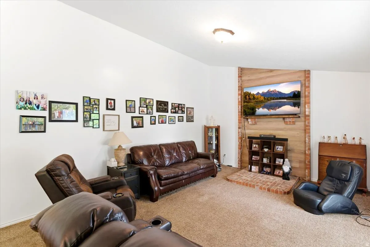 Living area featuring a brick and wood-paneled accent wall, a brick hearth, and wall-to-wall carpeting