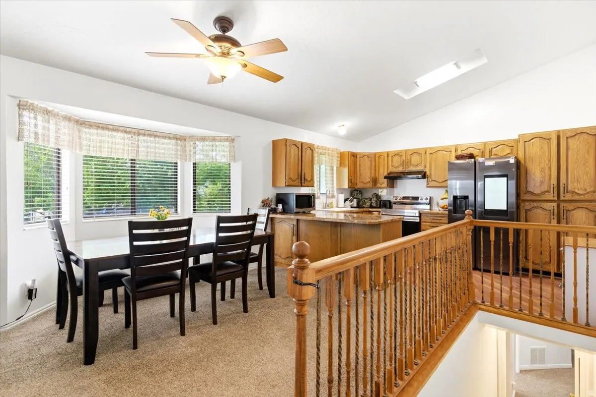 Open-concept kitchen and dining area featuring warm wood cabinetry, a central island with countertop seating, and a bay window