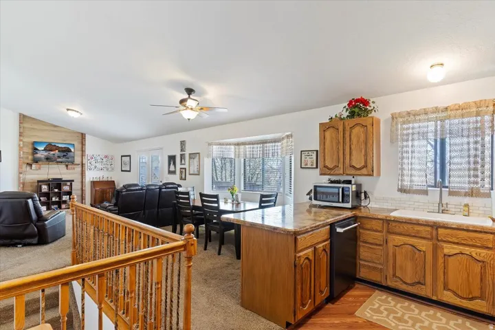 Open-concept kitchen featuring wood cabinetry, a built-in dishwasher, and a stone-finish countertop