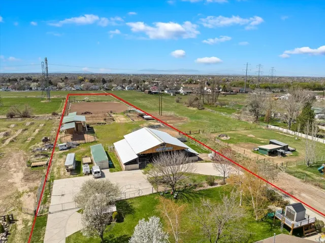 Expansive property featuring a large barn structure with a light-colored roof, a dirt riding arena, and multiple outbuildings