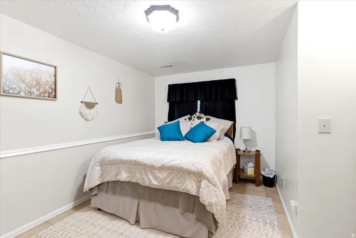 Bedroom featuring tile flooring, white walls, and a chair rail molding