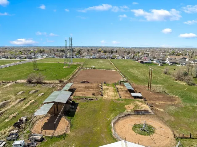 Expansive equestrian property featuring multiple fenced paddocks, covered stalls, and circular training pens