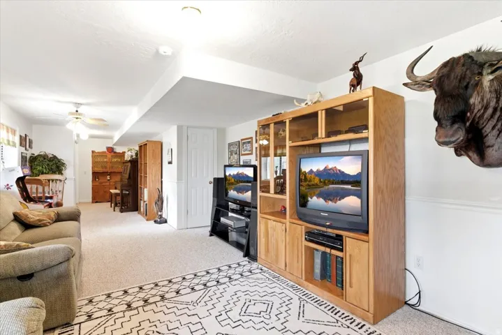 Spacious room featuring neutral carpeting, recessed lighting, and a built-in entertainment center with wood-finish cabinetry