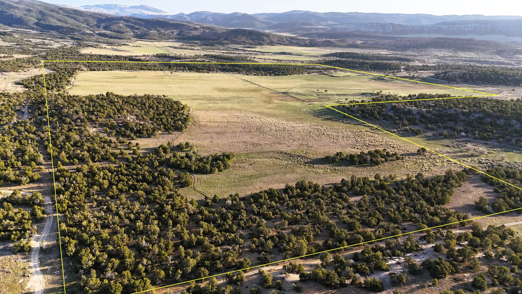 Aerial view of sparsely populated area with property boundaries highlighted and a mountain backdrop
