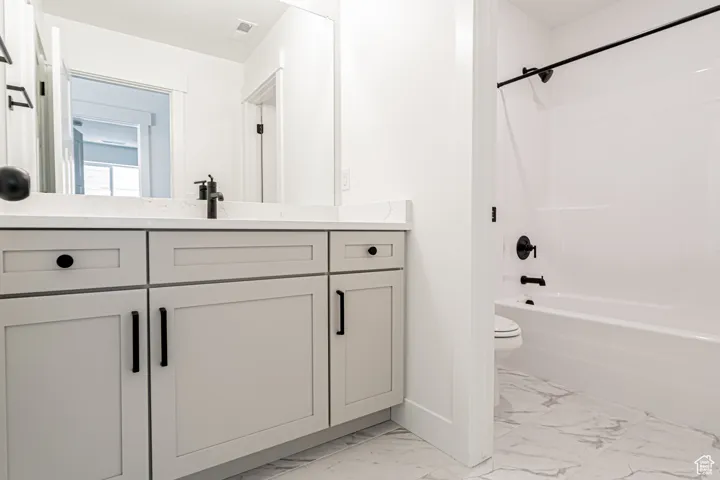 Full bath featuring marble finish floors, vanity, and tub / shower combination