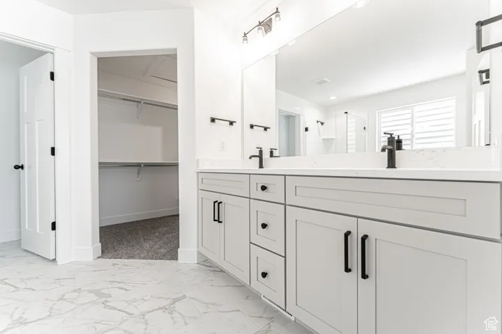 Bathroom featuring double vanity, a shower stall, marble finish floors, and a walk in closet
