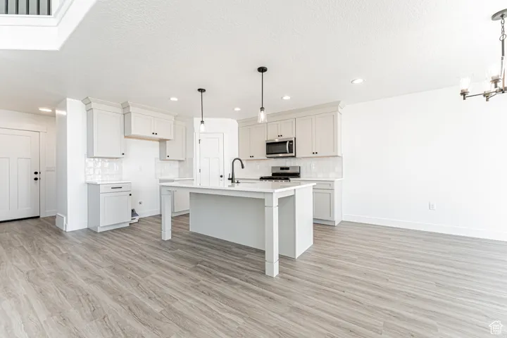 Kitchen featuring stainless steel appliances, a chandelier, tasteful backsplash, light countertops, and recessed lighting