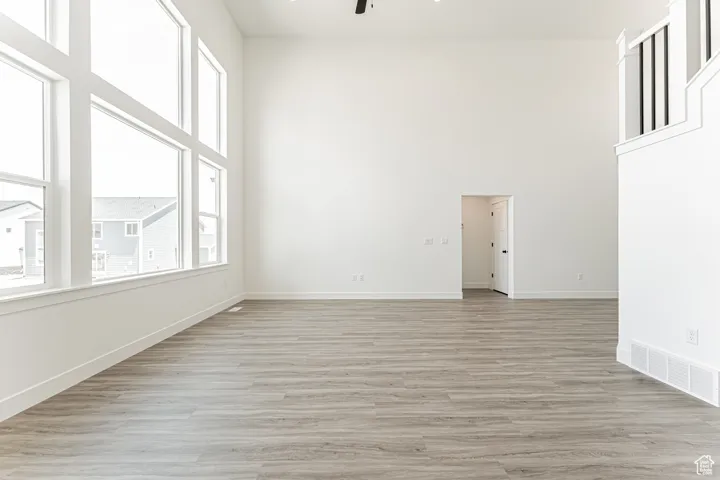 Unfurnished room with ceiling fan, a high ceiling, and light wood-style floors