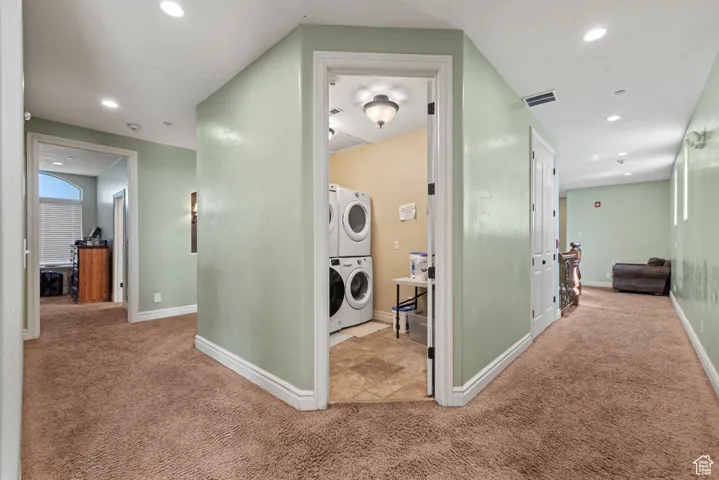 Corridor with recessed lighting, stacked washing maching and dryer, carpet, and visible vents