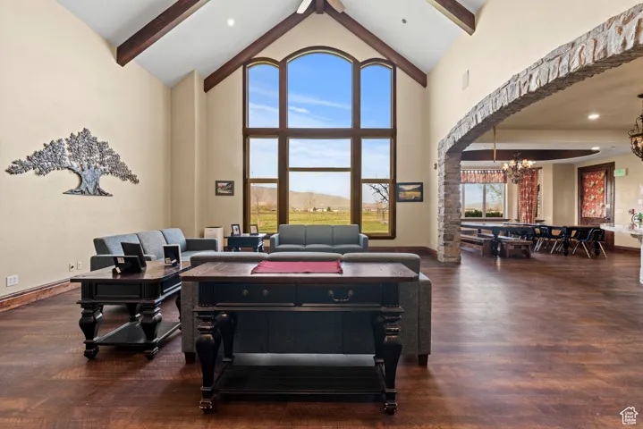 Game room featuring baseboards, an inviting chandelier, beam ceiling, wood finished floors, and high vaulted ceiling