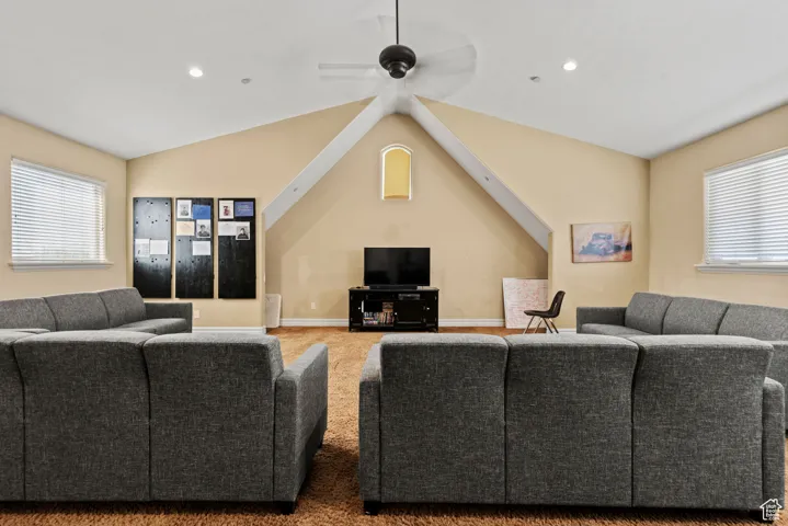 Carpeted living room with recessed lighting, lofted ceiling, baseboards, and ceiling fan
