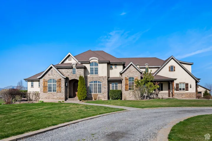 French country inspired facade featuring a front yard, brick siding, stucco siding, and stone siding