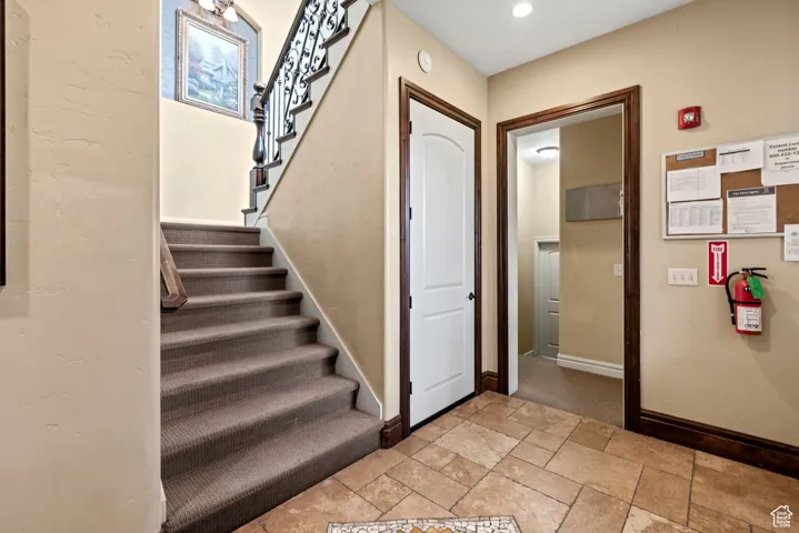 Staircase with stone tile floors and baseboards