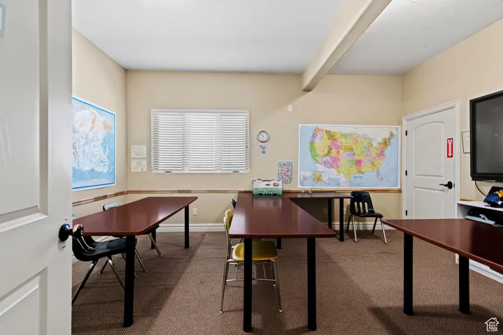 Home office featuring carpet, baseboards, and beam ceiling