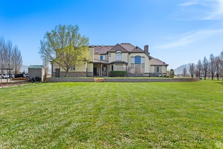 View of front of property with a front yard, a chimney, an outdoor structure, and stucco siding