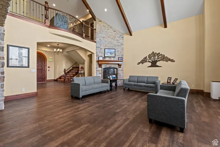 Living area featuring arched walkways, dark wood-style flooring, a fireplace, stairway, and high vaulted ceiling