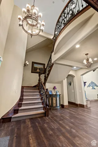 Staircase featuring arched walkways, recessed lighting, wood finished floors, a notable chandelier, and baseboards