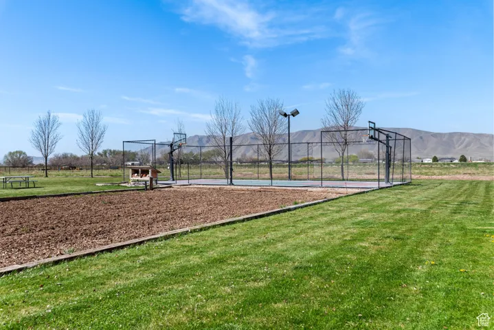 View of basketball court with community basketball court, a mountain view, fence, and a lawn