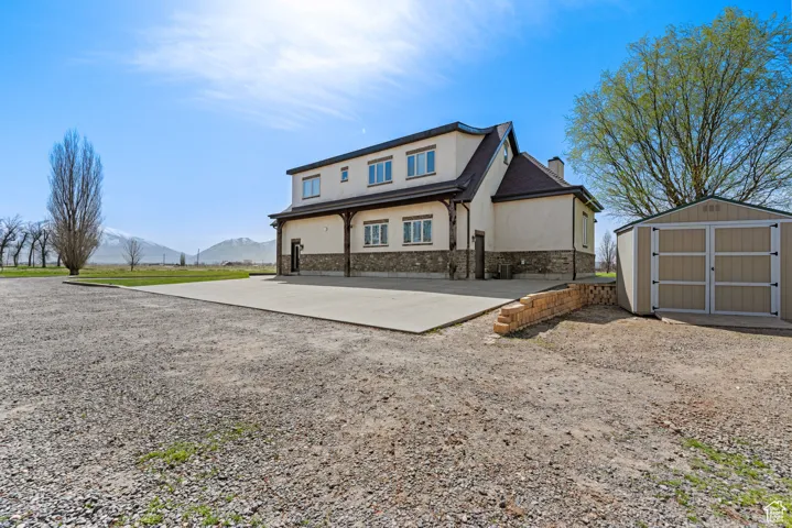 View of front of home featuring stucco siding, a chimney, a mountain view, an outbuilding, and a storage unit