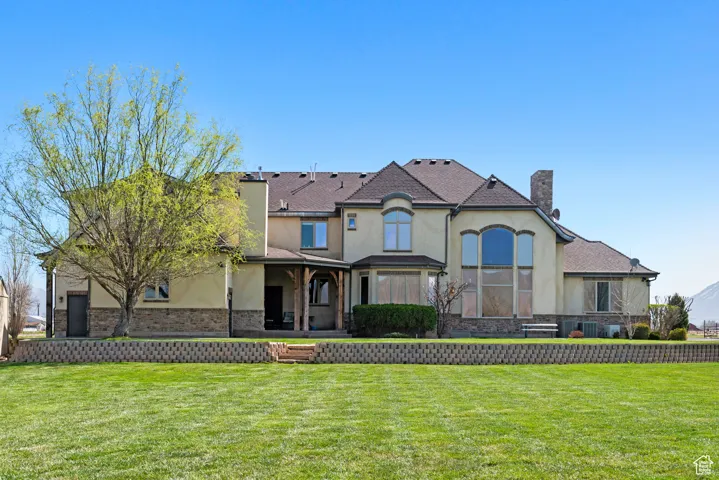 View of front of property featuring a front yard, stucco siding, and a chimney